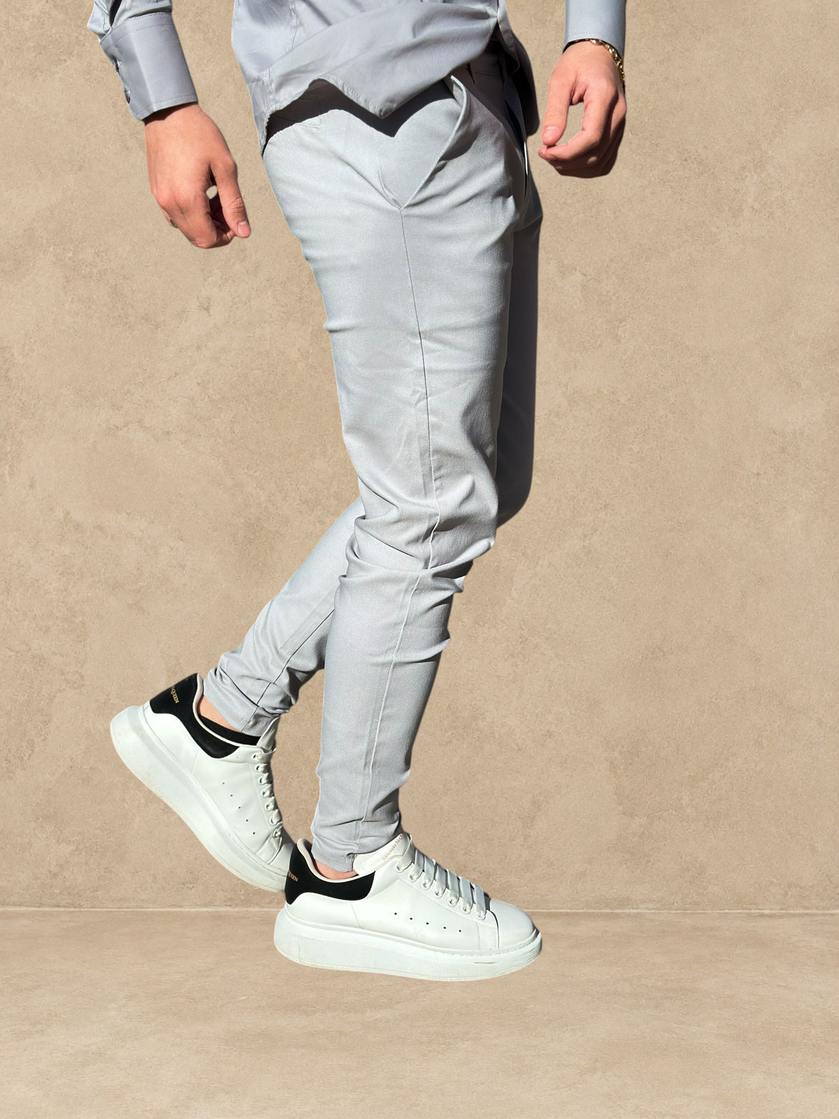 Pantalon Stayin gris à coupe cintrée et style pince, porté avec des baskets blanches à semelle épaisse en extérieur